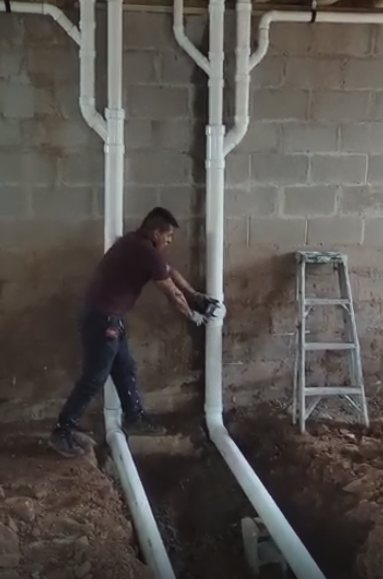 New PVC drain and vent lines run along a basement wall